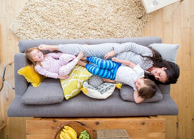woman and two young children on a couch enjoying warmth 